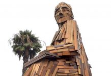 Imagen hecha en madera de Gabriela Mistral descansa sobre una silla mirando al mar